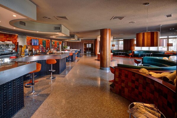 A modern bar area with a long counter, multiple stools, and a seating area with sofas and a coffee table. - Rey Sancho Ramirez (Barbastro)