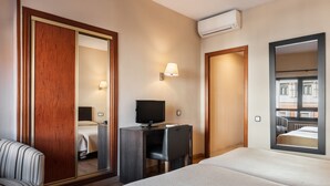 A hotel room with a bed, a desk with a computer, a chair, a TV, and a large mirror. - Crisol Riosol (León)