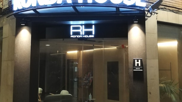 Entrada d'hotel amb un cartell de neó que diu "RONDA HOUSE" i un senyal que indica una classificació de 4 estrelles.