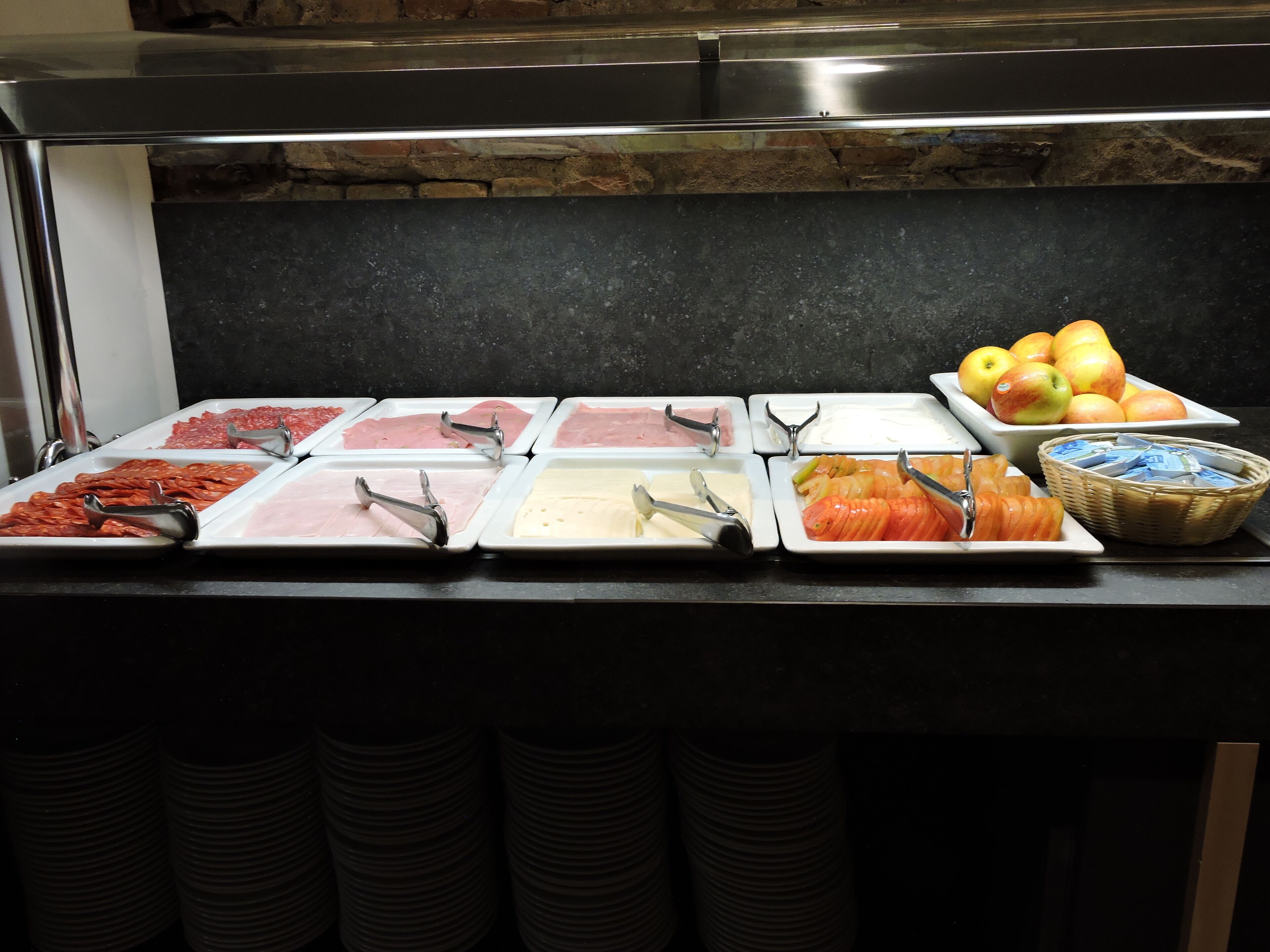 Un buffet proposant une variété de plats, notamment des viandes, des fromages et des fruits.
