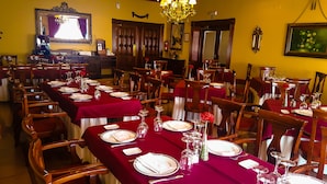 A dining area with tables set for multiple guests, featuring red tablecloths, white plates, and clear glassware. - Salvador Hotel (Bailen)