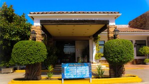 A hotel entrance with a covered patio, a signboard, and well-maintained landscaping. - Salvador Hotel (Bailen)