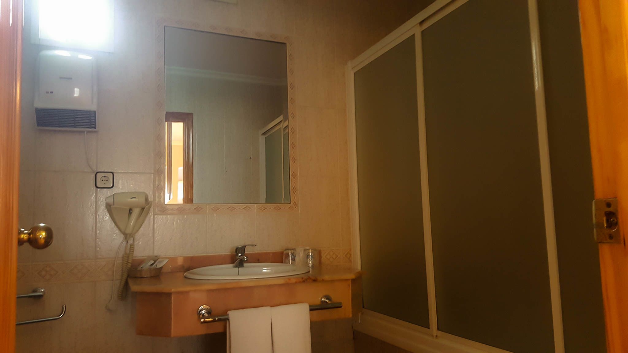 Un baño con lavamanos, espejo y zona de ducha.