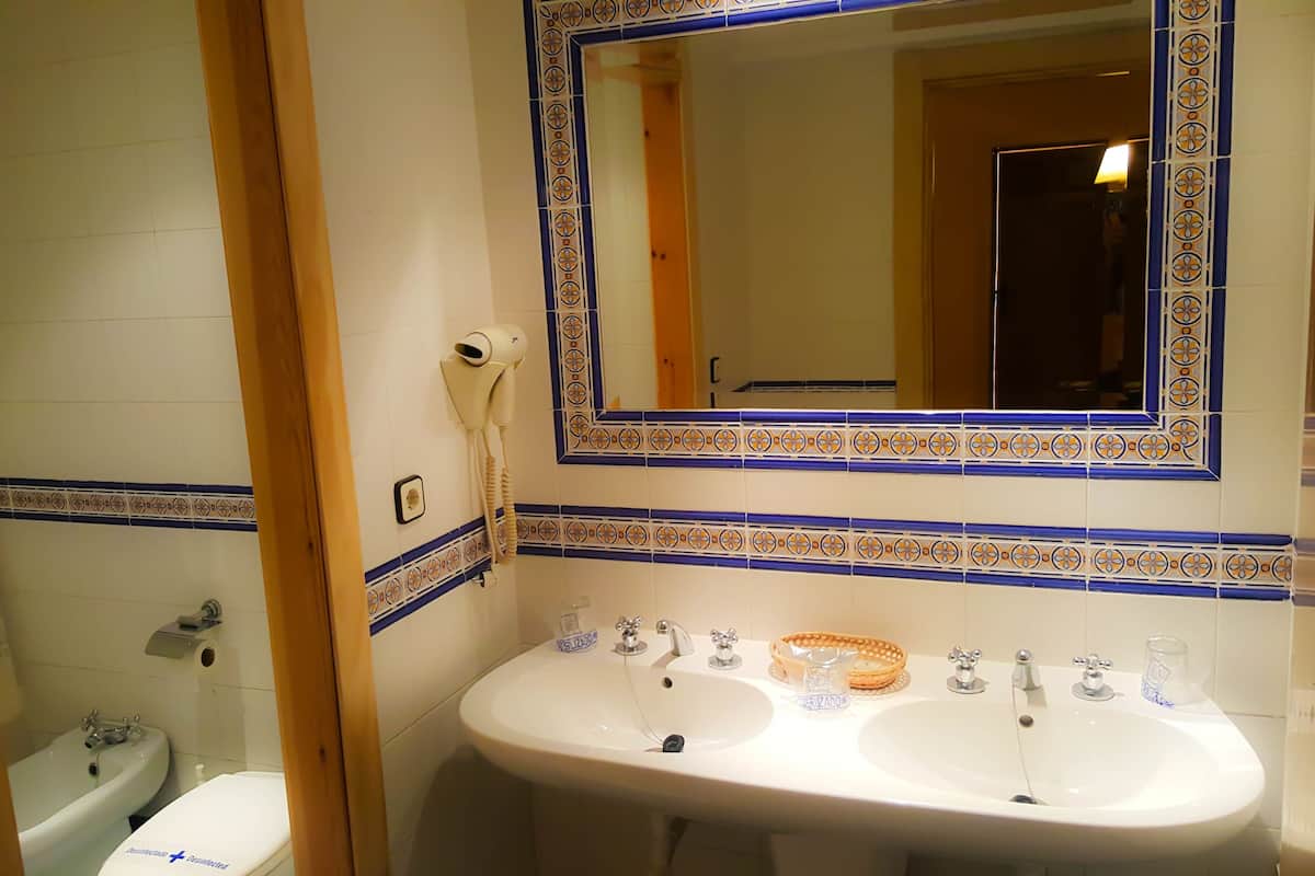 A bathroom with two sinks, a mirror, and a toilet.