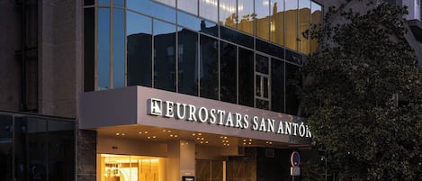 Un hotel moderno con fachada de vidrio, llamado "Eurostars San Anton".