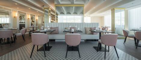 A modern restaurant with a patterned floor, cushioned seating, and a bar area.