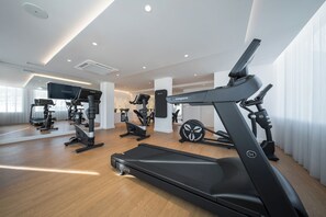 Un gimnasio moderno con diversos equipos de cardio y entrenamiento de fuerza, incluyendo cintas de correr y máquinas de pesas.
