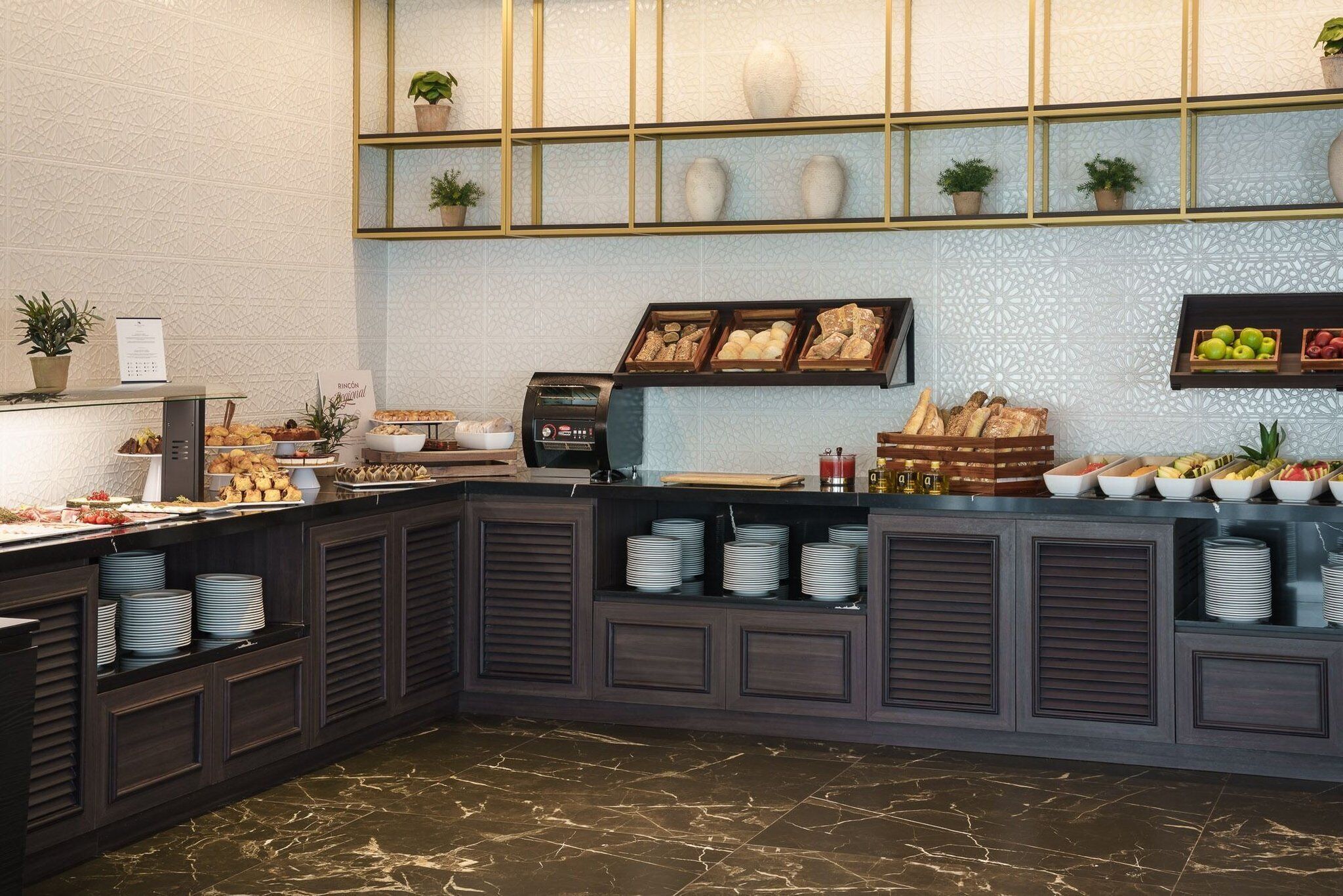 A buffet setup with various food items, a coffee machine, and a decorative wall with plants.