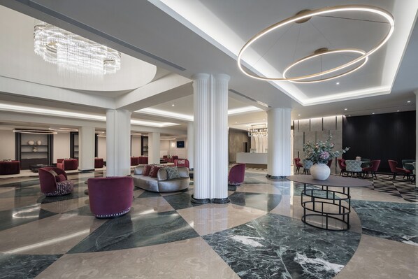 A spacious lobby with high ceilings, marble flooring, and modern furniture. - Eurostars San Anton (Granada)