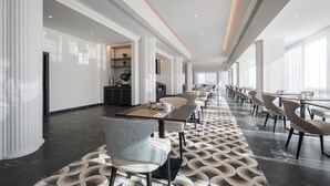 Un moderno vestíbulo de hotel con un mostrador de recepción alargado, zona de estar y ventanas amplias.