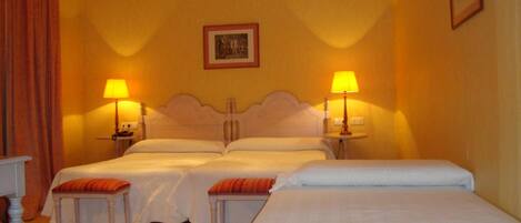 A hotel room with two beds, a small table, two lamps, and a picture on the wall.