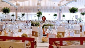 Un salón de banquetes con mesas redondas dispuestas para un evento formal, con manteles blancos, cristalería y centros de mesa florales.