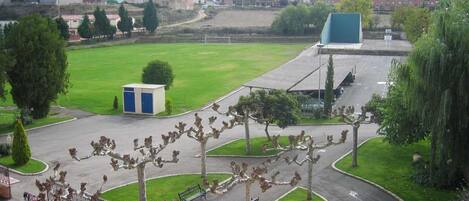 Un estacionamiento con un campo verde, un pequeño edificio azul y una estatua de caballos.