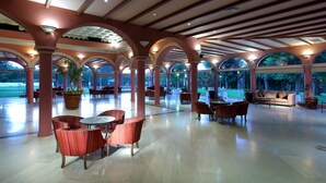 Un espacio interior amplio con varios arreglos de asientos, ventanas grandes y un techo alto con vigas de madera.