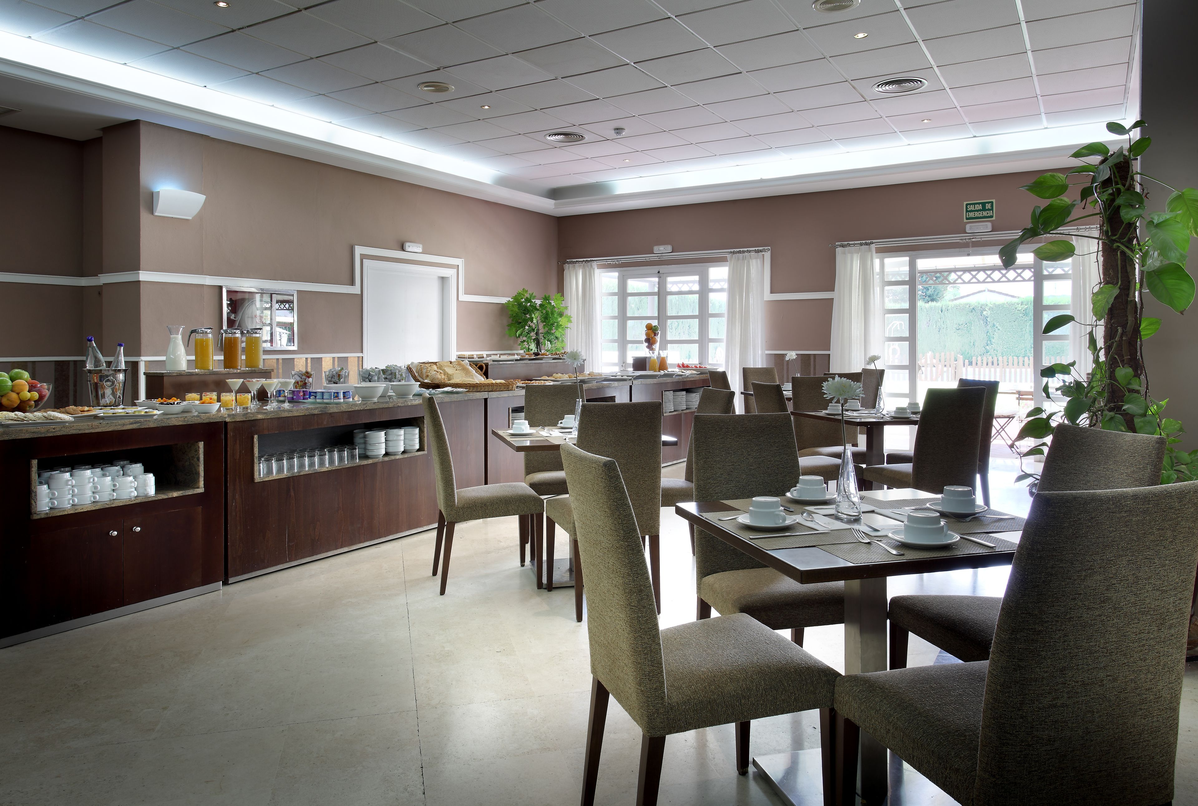 A dining area with a buffet, chairs, and a plant.