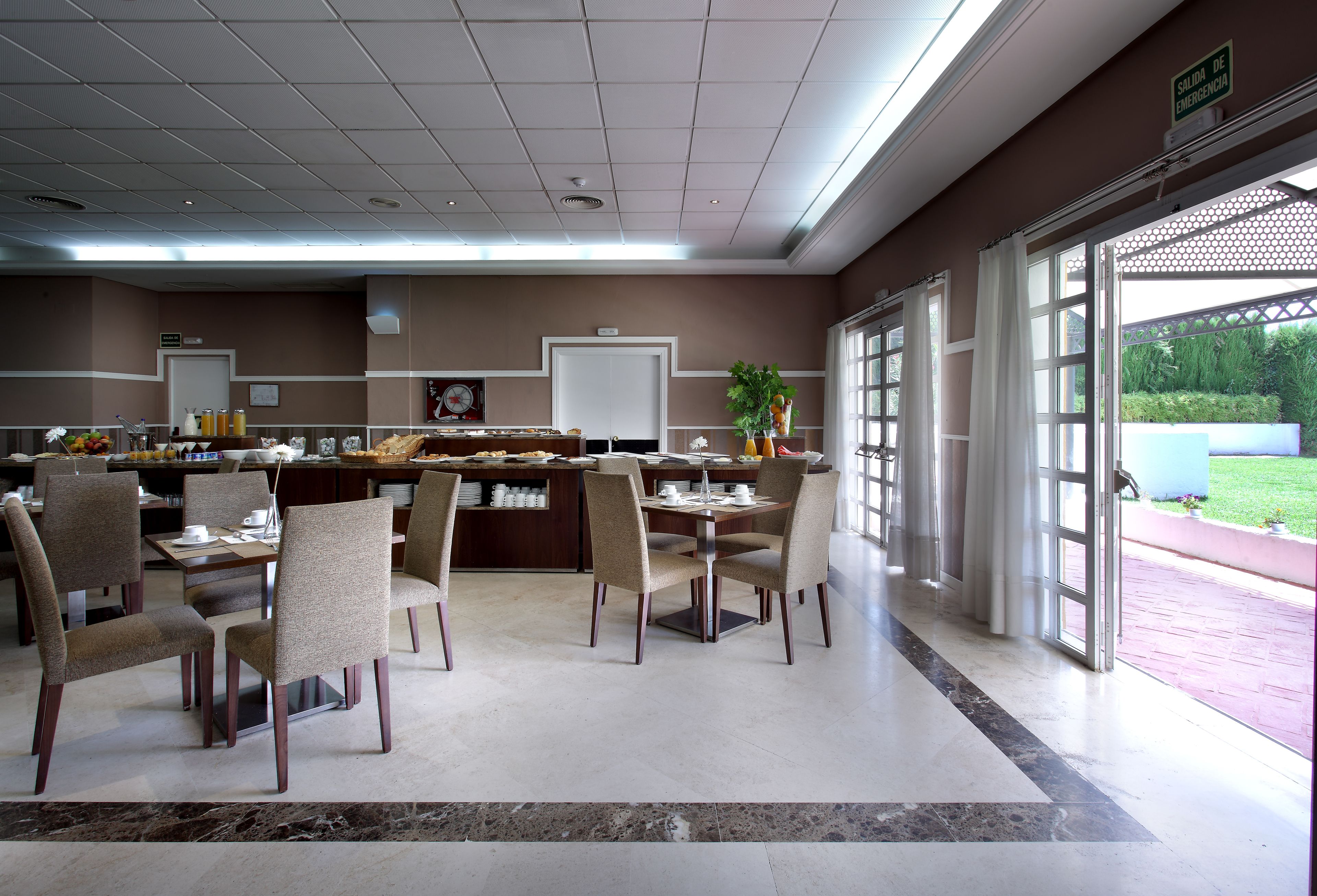 A dining area with a buffet setup, a reception desk, and a view of the outdoors.