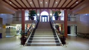Una imponente escalera conduce a una entrada arqueada, flanqueada por macetas con plantas y barandillas de metal.