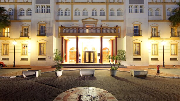 Un hotel grande de varios pisos con una entrada imponente, múltiples balcones y una fachada bien iluminada.