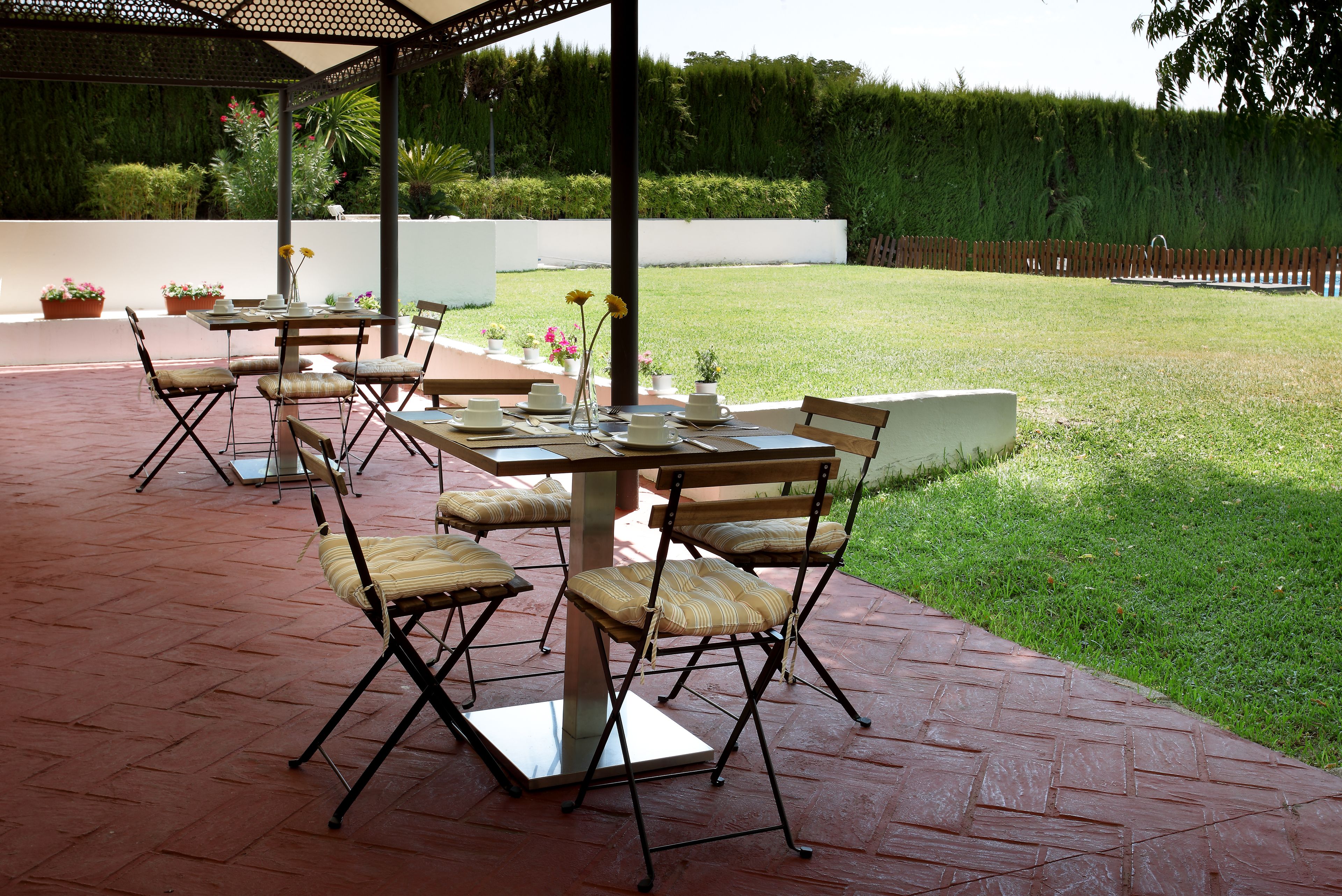 Un patio exterior con una mesa lista para comer, rodeado de sillas.
