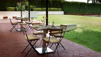 Un patio exterior con una mesa lista para comer, rodeado de sillas.