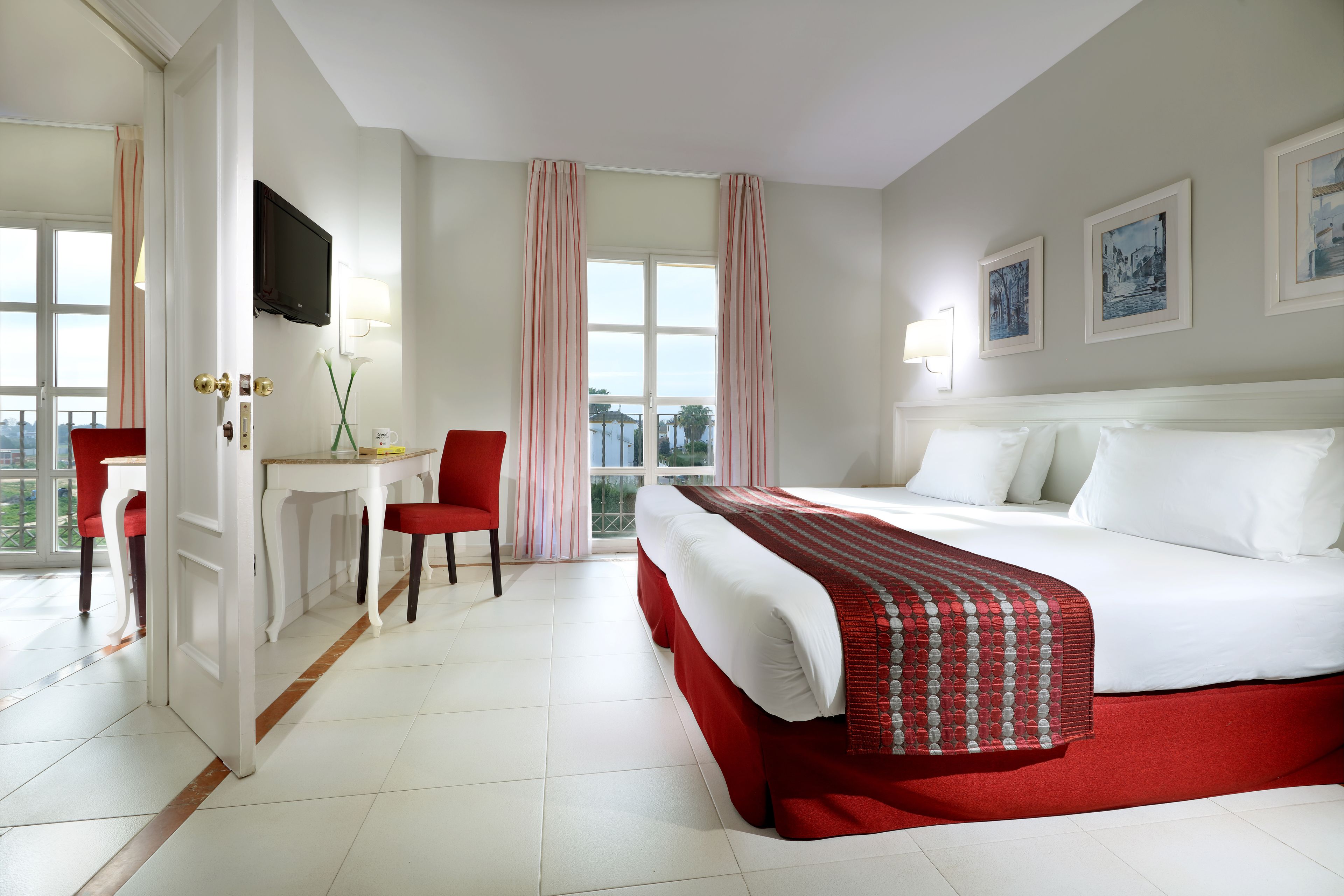 Habitación de hotel con una cama grande, un escritorio, una silla y un televisor.