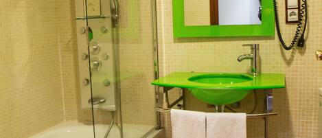 A bathroom with a glass-enclosed shower, a green sink, and a mirror with a green frame.