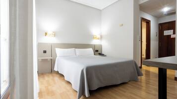 Una habitación de hotel con una cama, mesitas de noche y lámparas de pared.