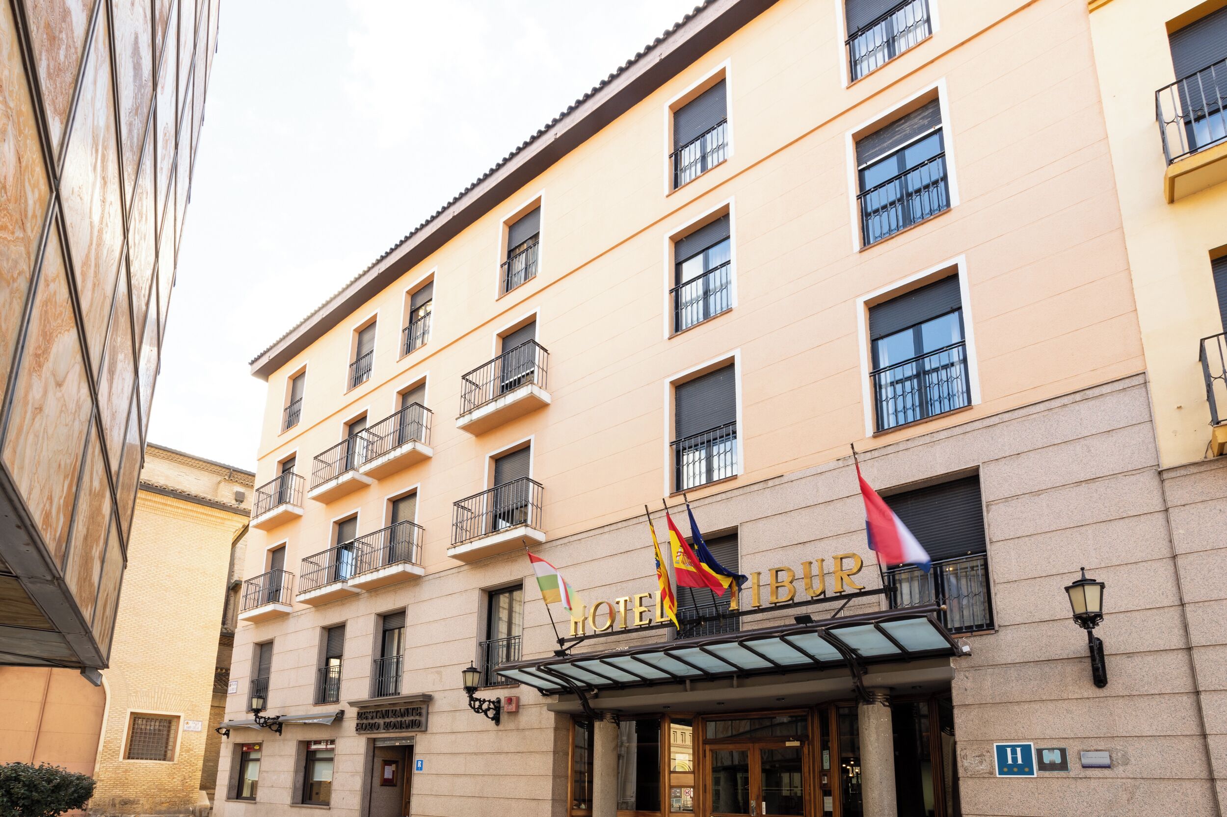 Een hotel met een klassiek gevelontwerp, meerdere balkons en een opvallende ingang met vlaggen.