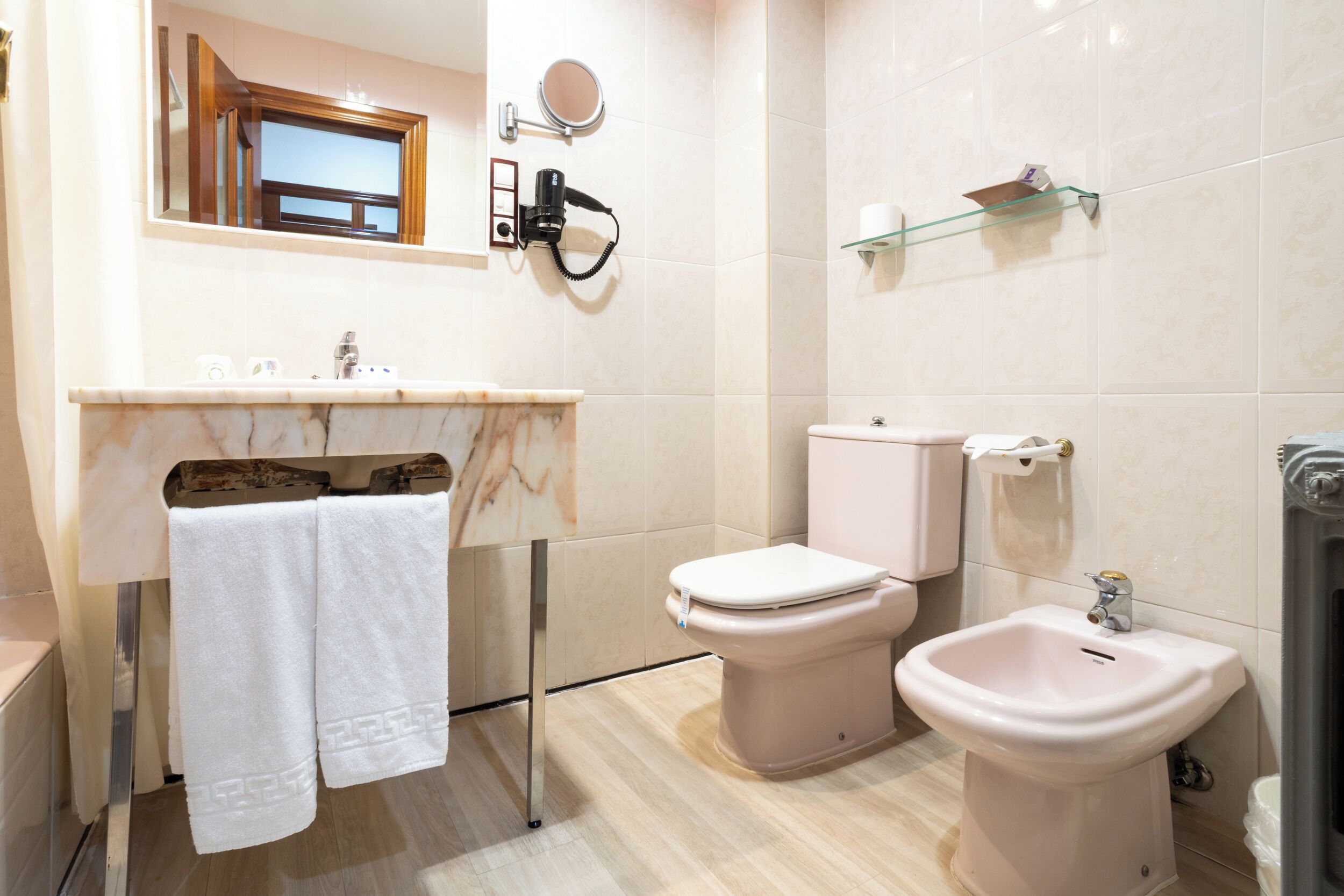 A bathroom with a marble sink, a toilet, a bidet, and a mirror.