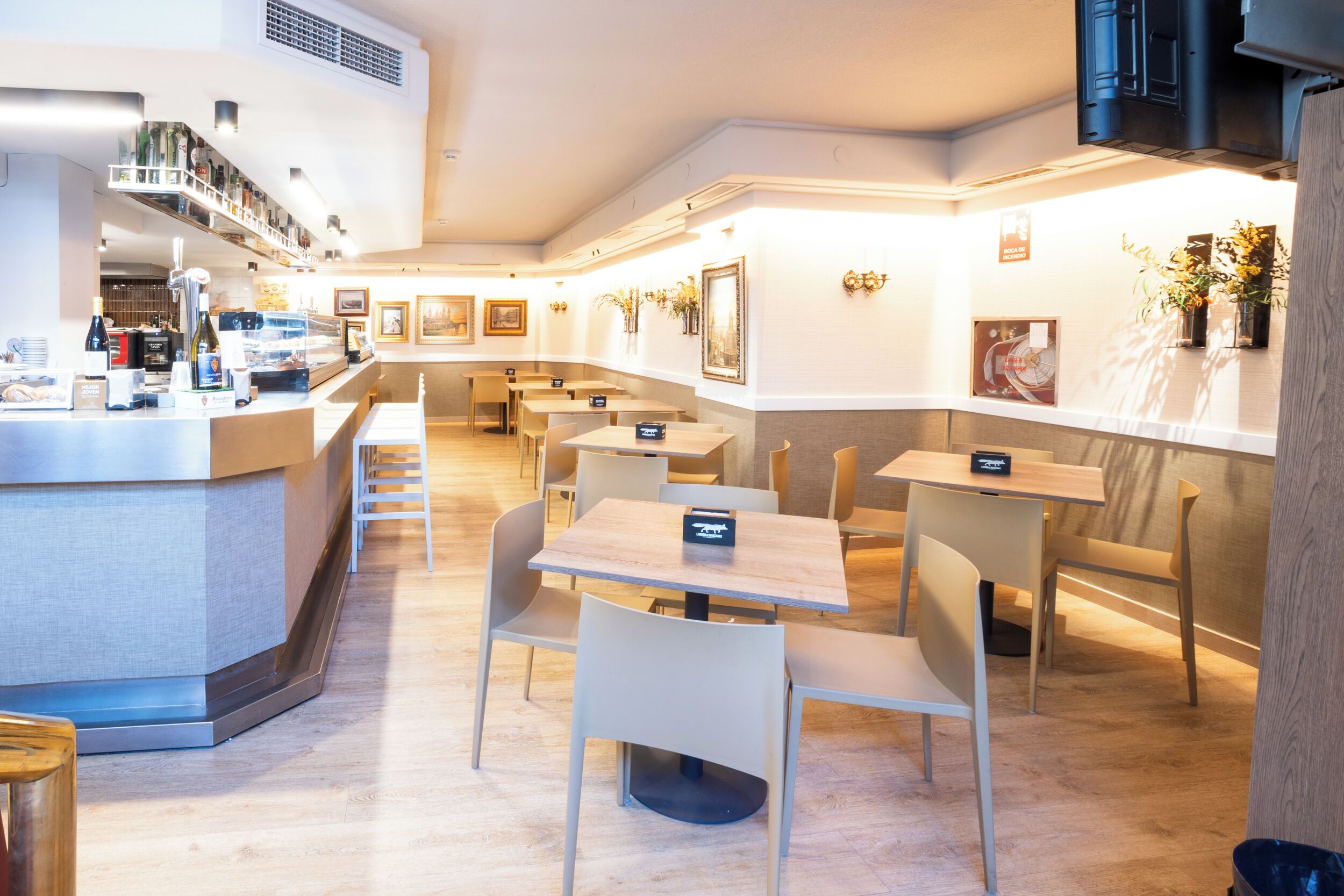 Un restaurante moderno con zona de bar, diversas opciones de asientos y un interior limpio y bien iluminado.