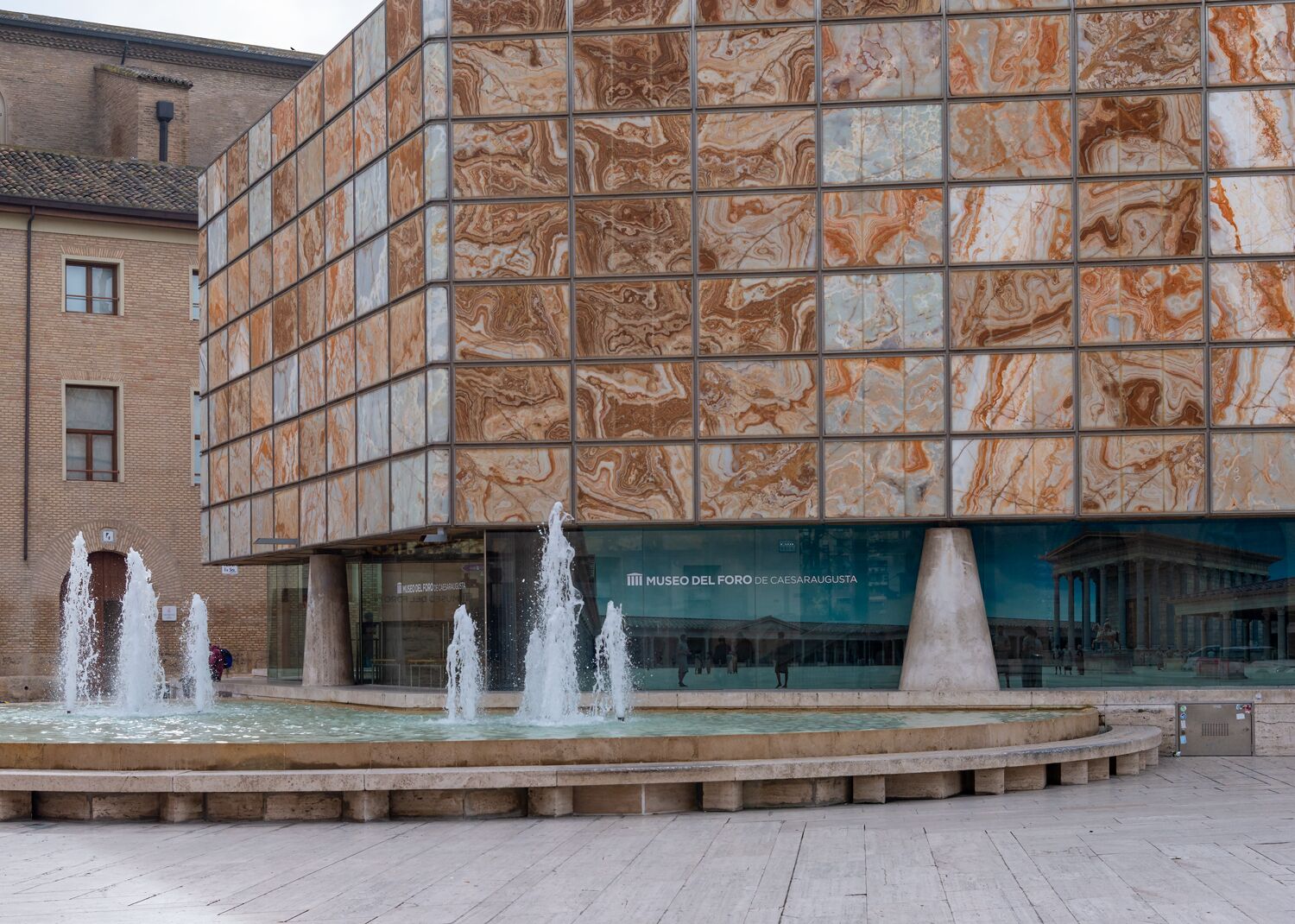 A modern building with a marble facade and a central fountain.