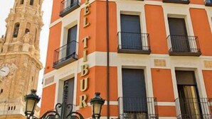 A hotel with a prominent clock tower in the background, featuring a classic architectural style with a clock on its facade. - Tibur Hotel (Zaragoza)
