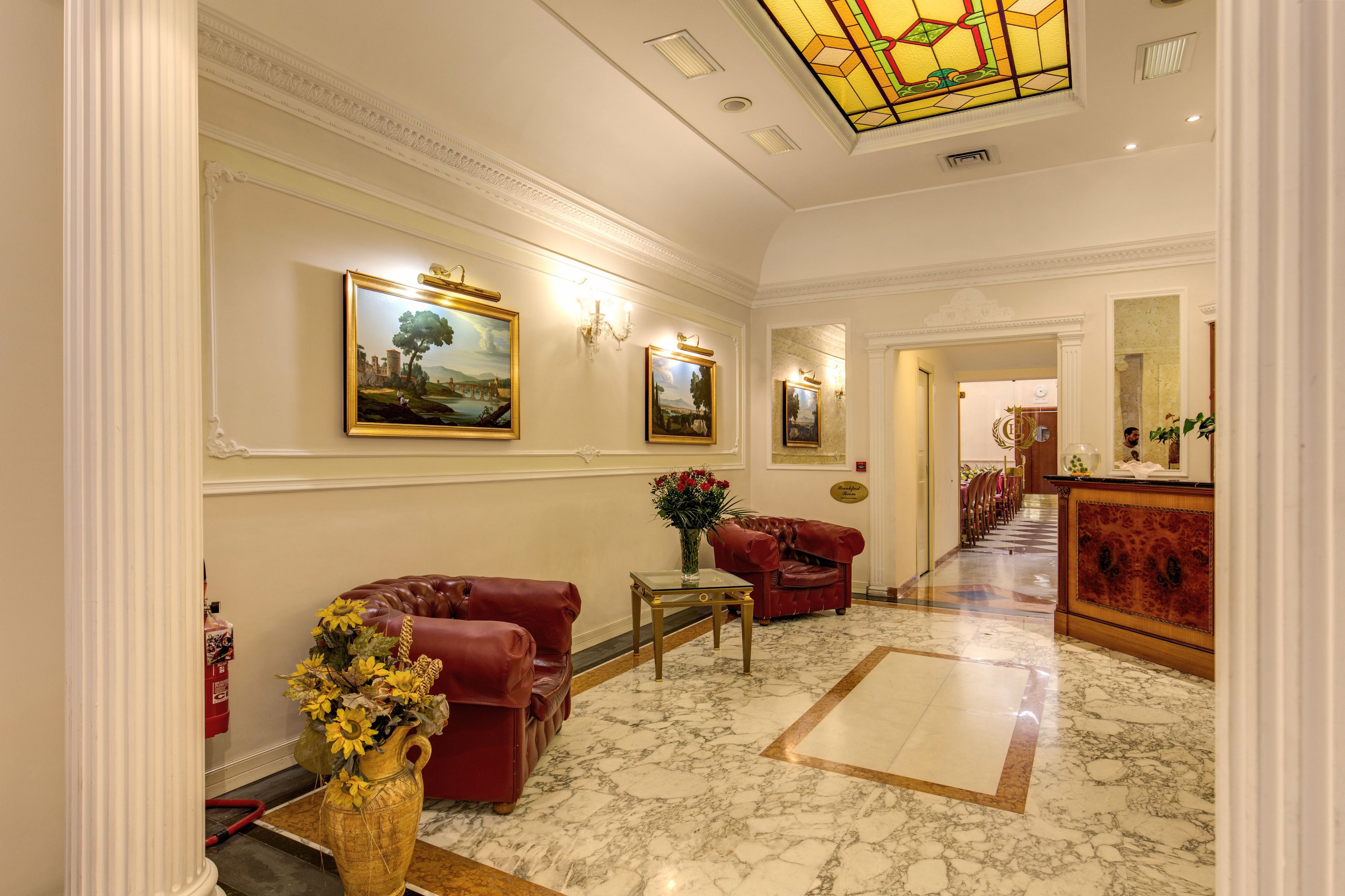 A spacious lobby with marble flooring, red leather sofas, and framed artwork on the walls.