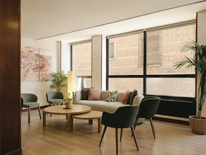 A modern living room with a sofa, chairs, a coffee table, and a large window with a view of a stone building. - Sercotel Toledo Imperial (Toledo)