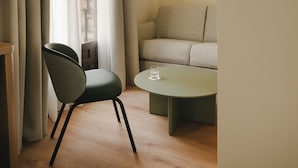 A room with a round table, a chair, a sofa, and a window with curtains. - Sercotel Toledo Imperial (Toledo)