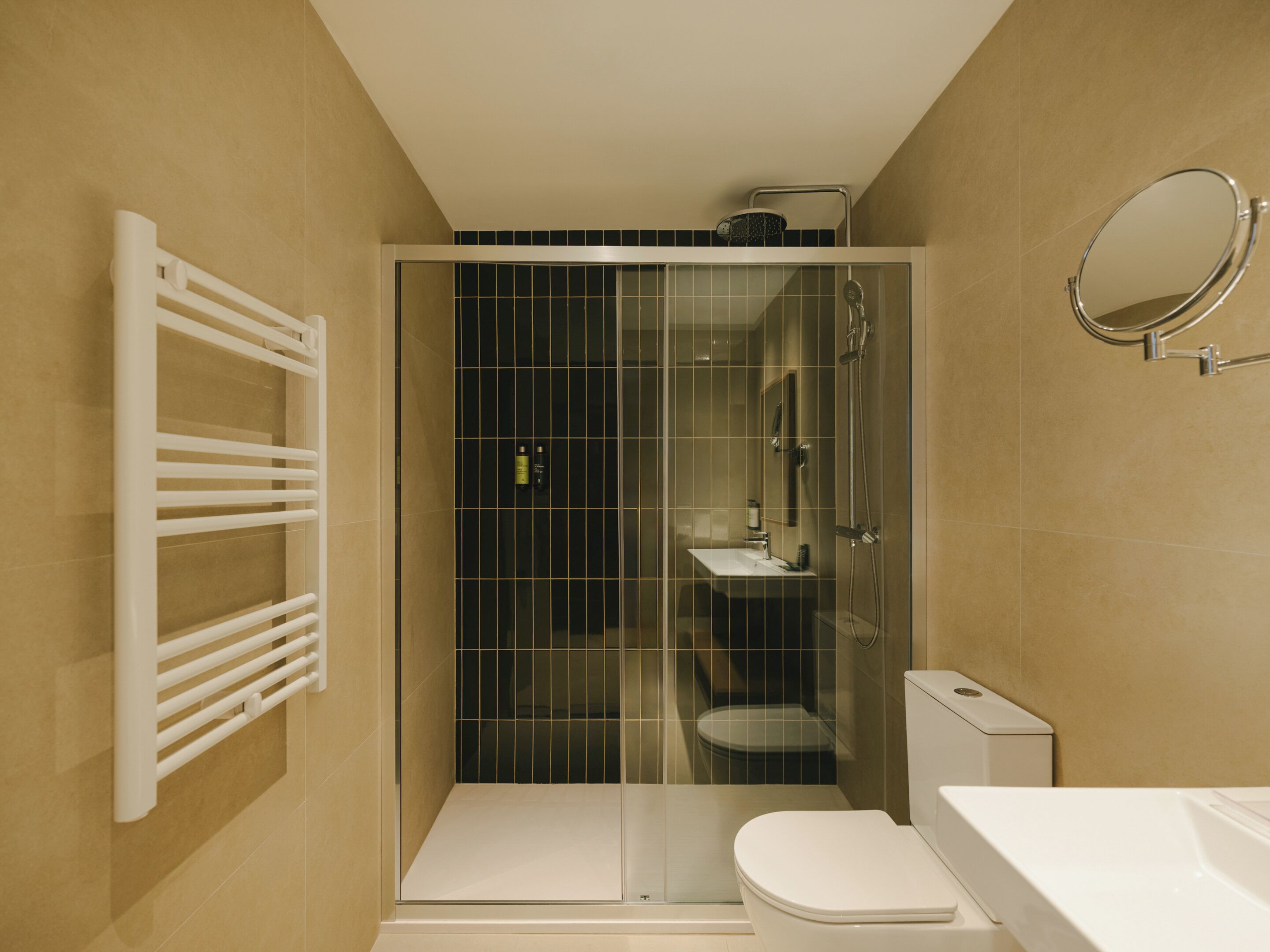 Een moderne badkamer met een douchecabine van glas, een wit toilet en een wastafel.