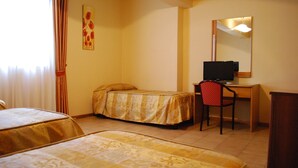 Habitación de hotel con dos camas individuales, un escritorio con silla, televisor y espejo.