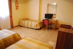 Una habitación de hotel con dos camas, un escritorio con una computadora, una silla y un armario de madera.