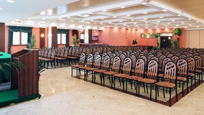 Un salón de conferencias con filas de sillas, un atril y un escenario.