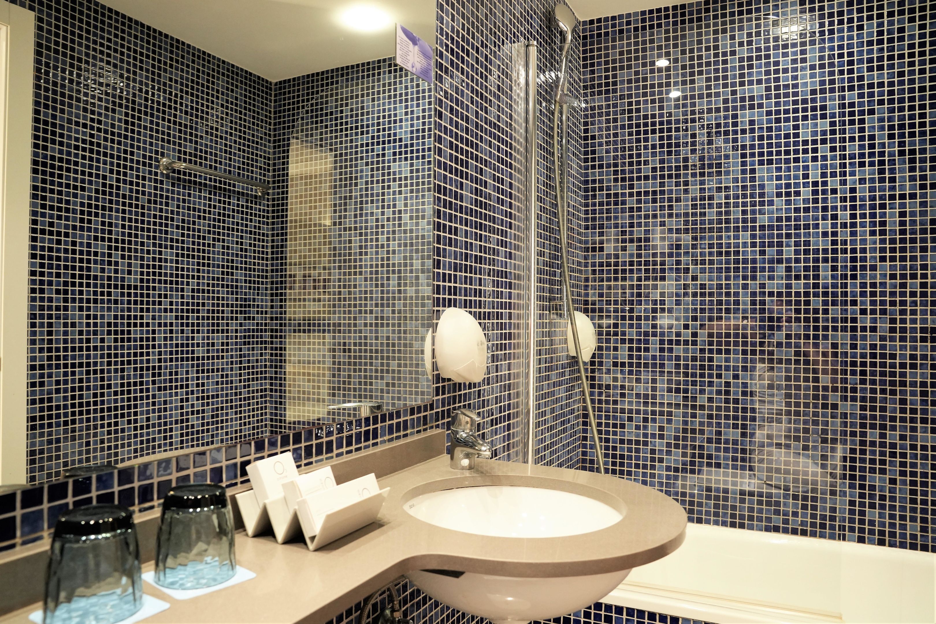 A bathroom with a large sink, mirror, and shower.