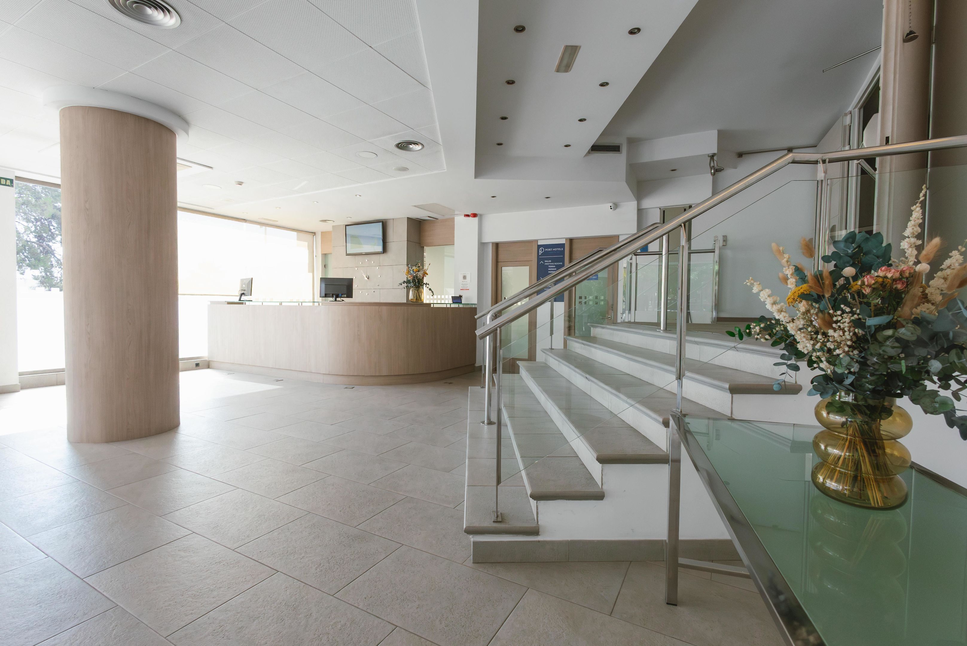 Un espace d’accueil moderne comprenant un comptoir de réception, un escalier et une rambarde en verre.