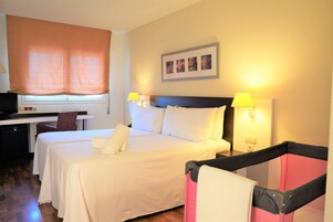 Habitación de hotel con dos camas, un escritorio, una silla y una ventana con persianas.