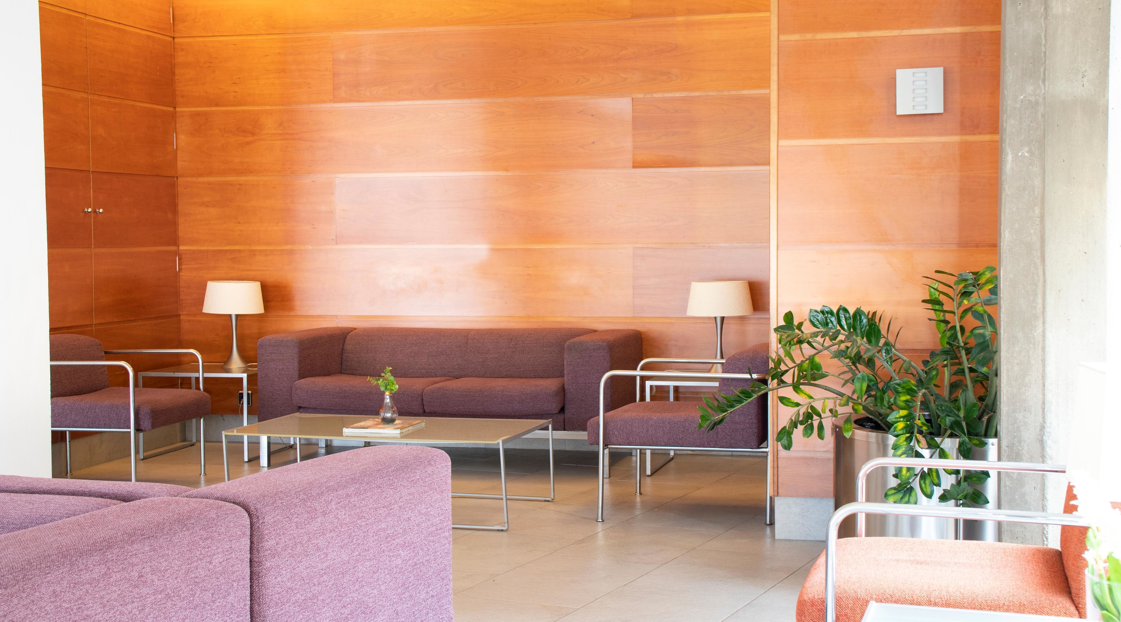 A modern waiting area with a sofa, armchairs, a coffee table, and a potted plant.
