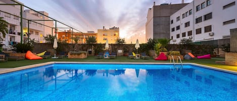 A swimming pool with lounge chairs and a view of buildings in the background.