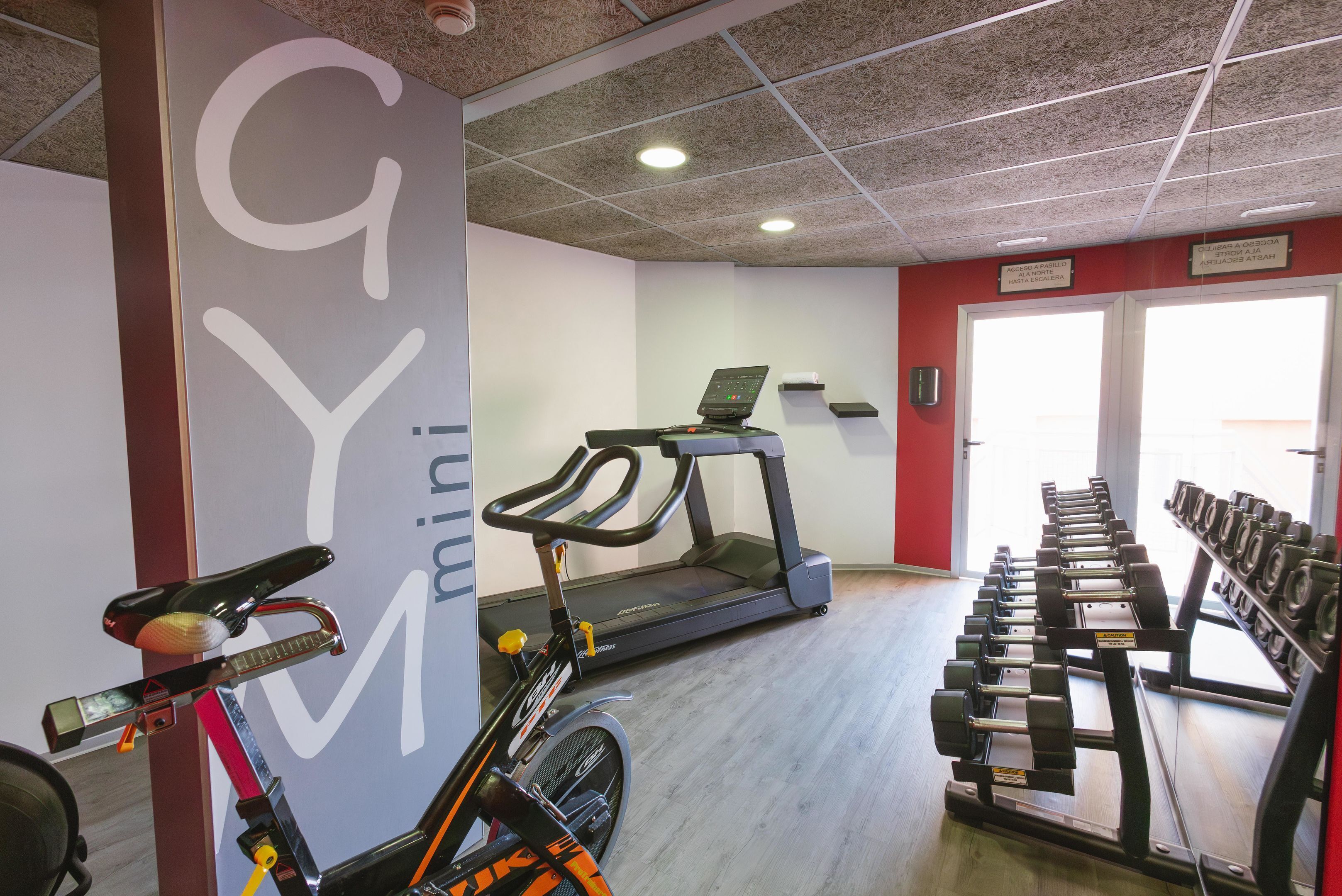 Ein Fitnessstudio mit Ergometer, Laufband und Kurzhanteln.