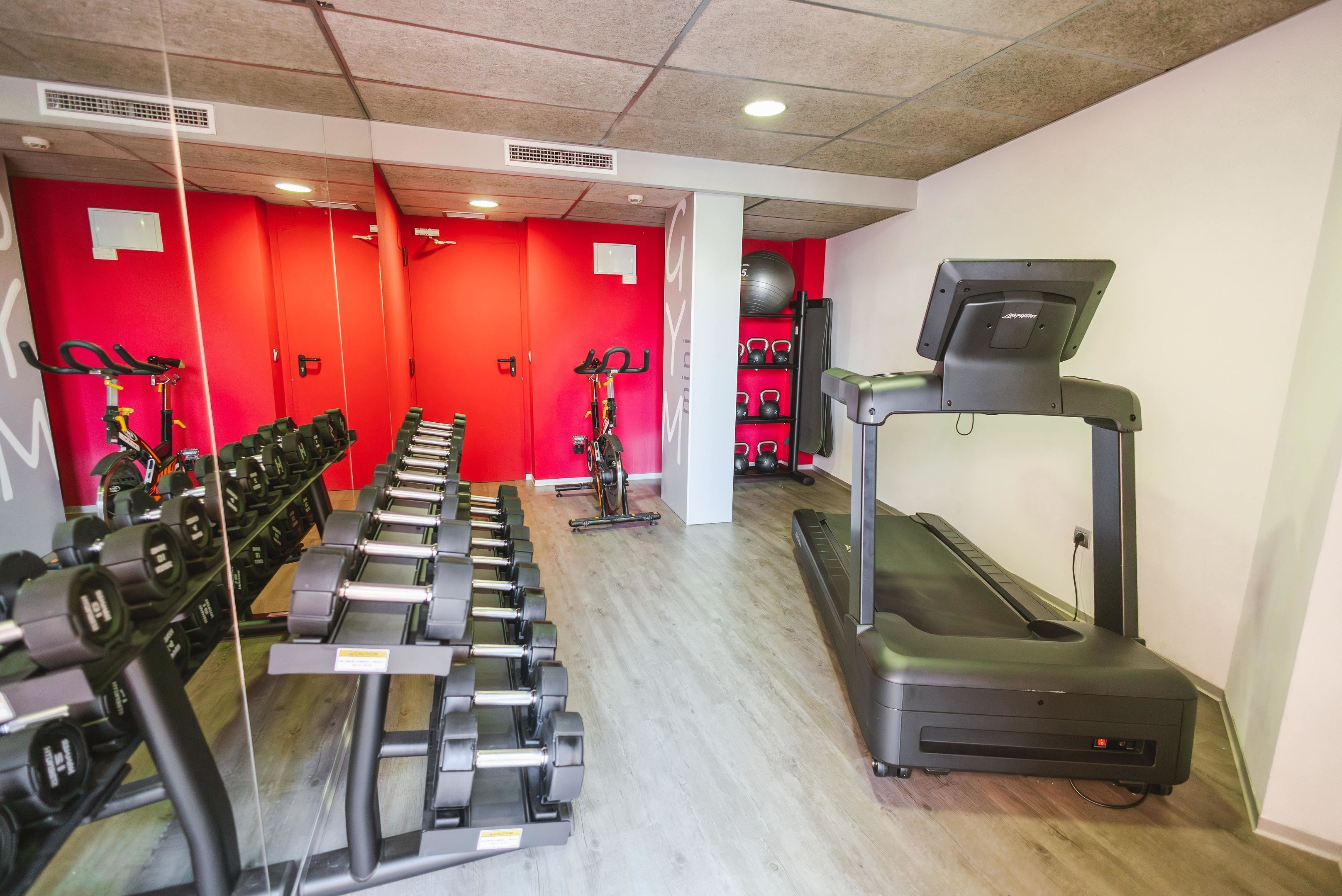 Un gimnasio con cintas de correr, bicicletas estáticas y mancuernas.