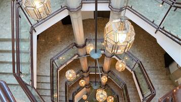 A multi-level interior with a central staircase, multiple light fixtures, and a polished stone floor.