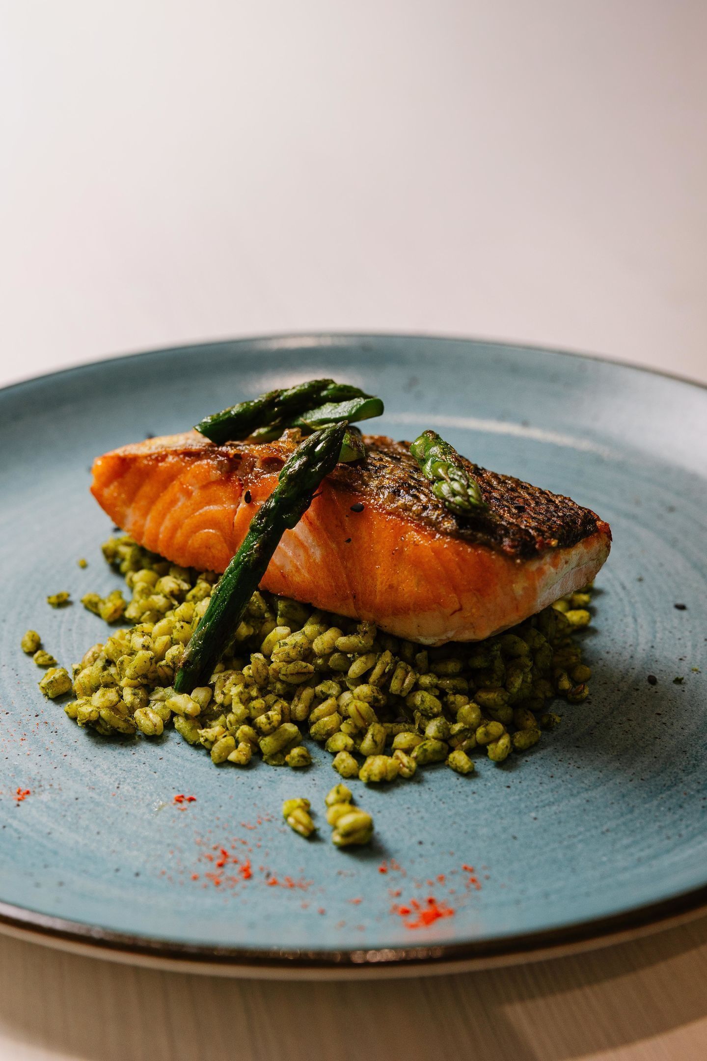 Un plato con salmón, espárragos y risotto verde.