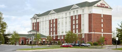 A large brick building with a sign reading "Hilton Garden Inn." It features multiple windows and a green roof.