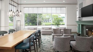 A modern dining area with a wooden table and chairs, a fireplace, and large windows offering a view of the outdoors.